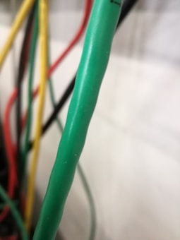 Several colorful cables are shown with green, red, yellow, and black colors prominently visible. The green cable is in focus, while the others are blurred in the background.