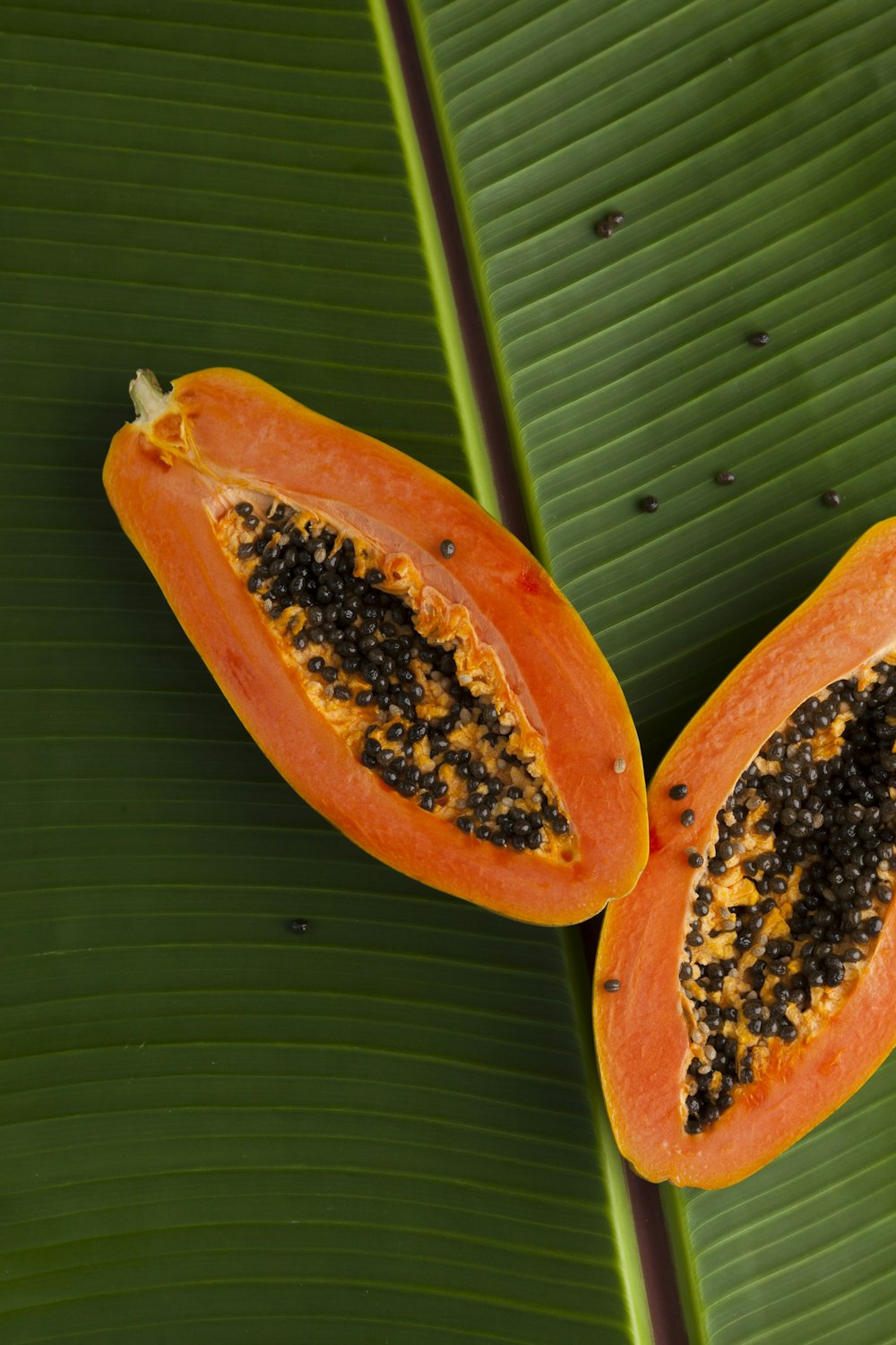 Papaya en rodajas sobre hoja de plátano verde