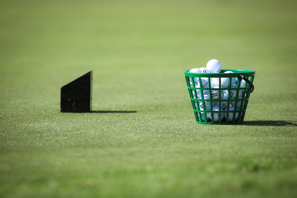 canasta de pelotas de golf sobre hierba verde