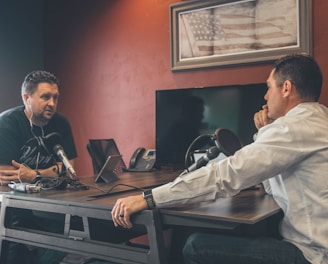 man sitting in front of another man also sitting inside room