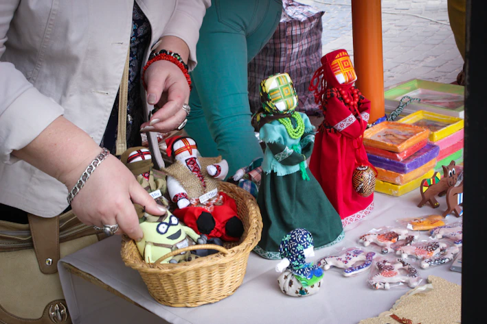 Close-up of colorful handmade amigurumi dolls arranged on a wooden table with soft forest-themed background lighting