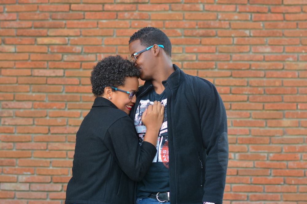 man kissing the forehead of woman