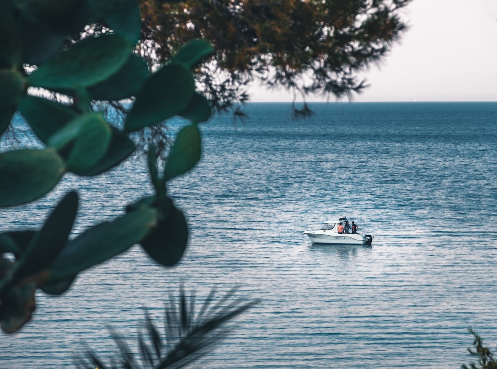 three persons riding boat on calm seat at daytime