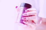 fingers with strong nails holding pink container