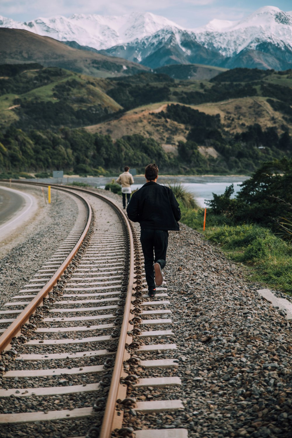 a couple of people walking down a train track