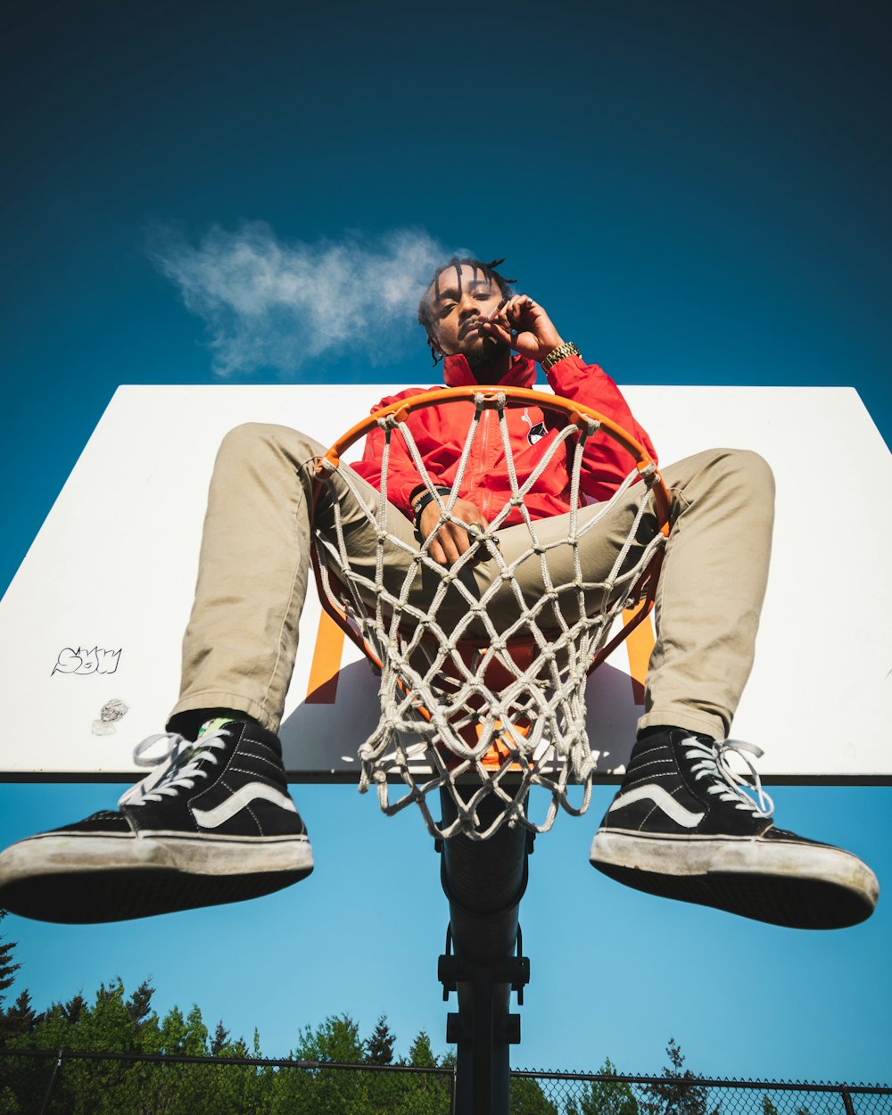 man in red jacket sitting on basketball ring