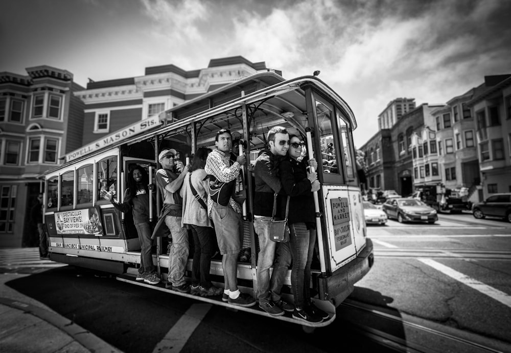grayscale photography of group of person riding on vehicle