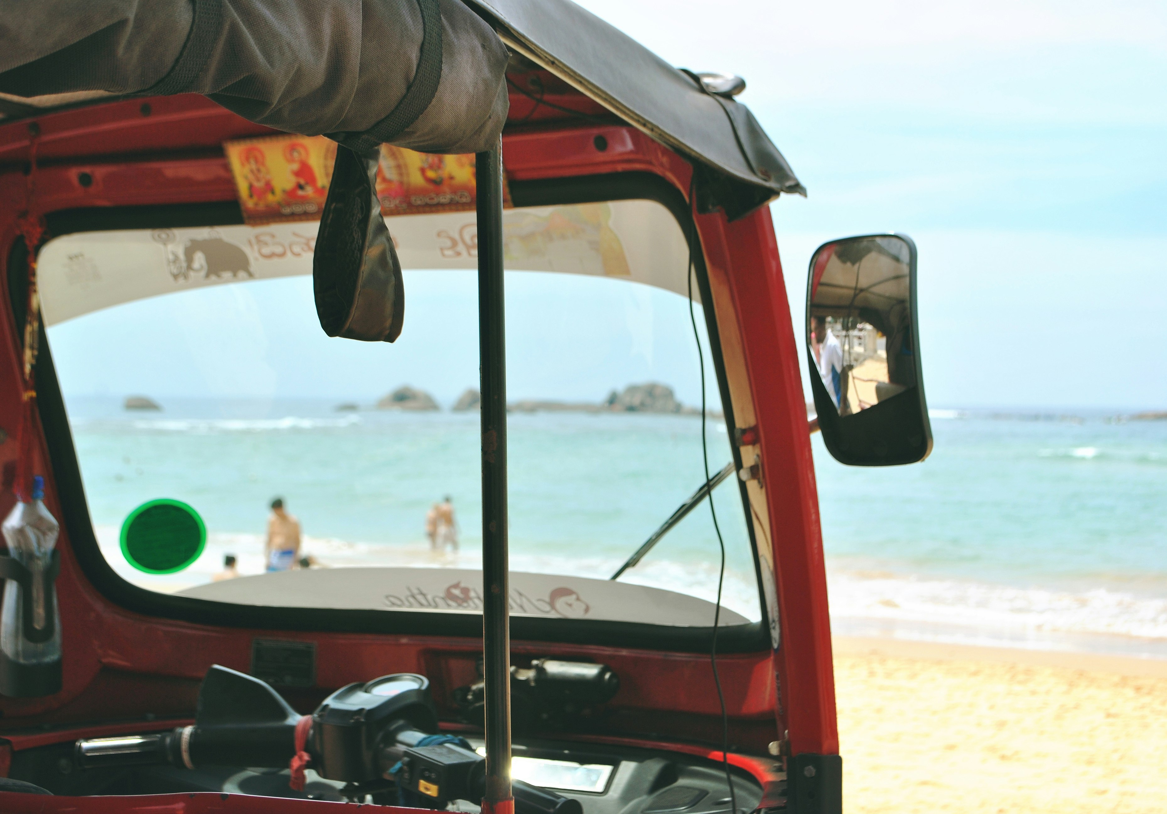 photo of red auto-rickshaw facing sea