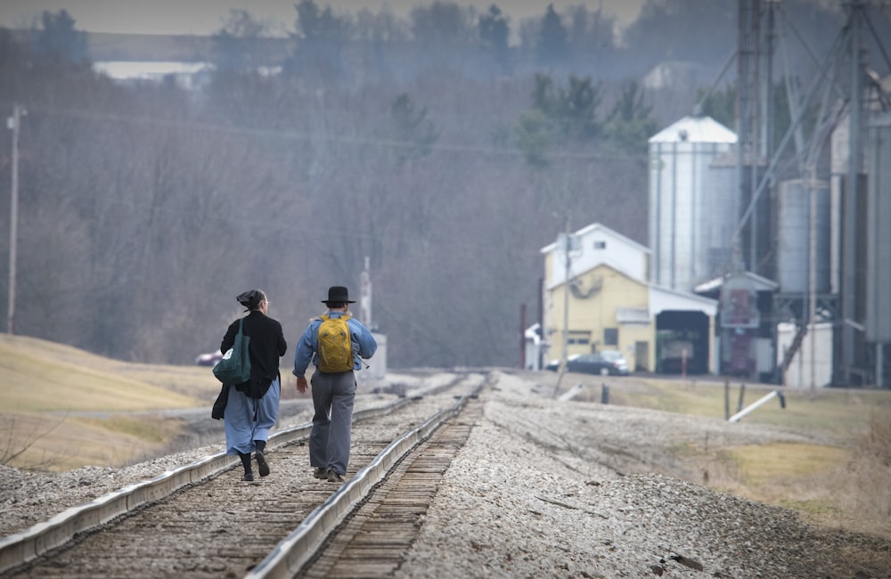a couple of people walking down a train track
