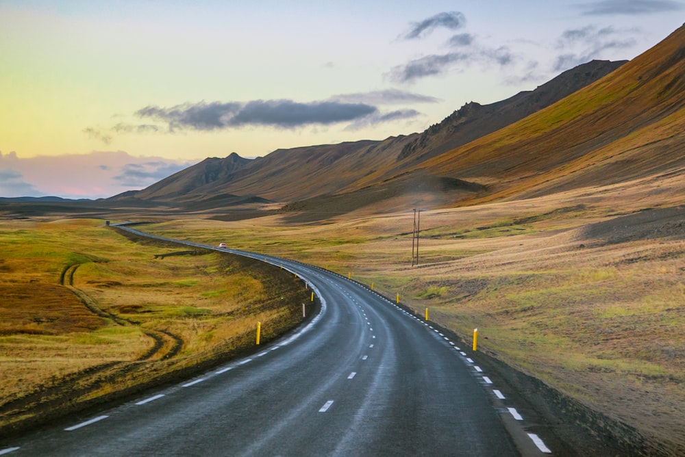 empty roadway between grass field during daytime