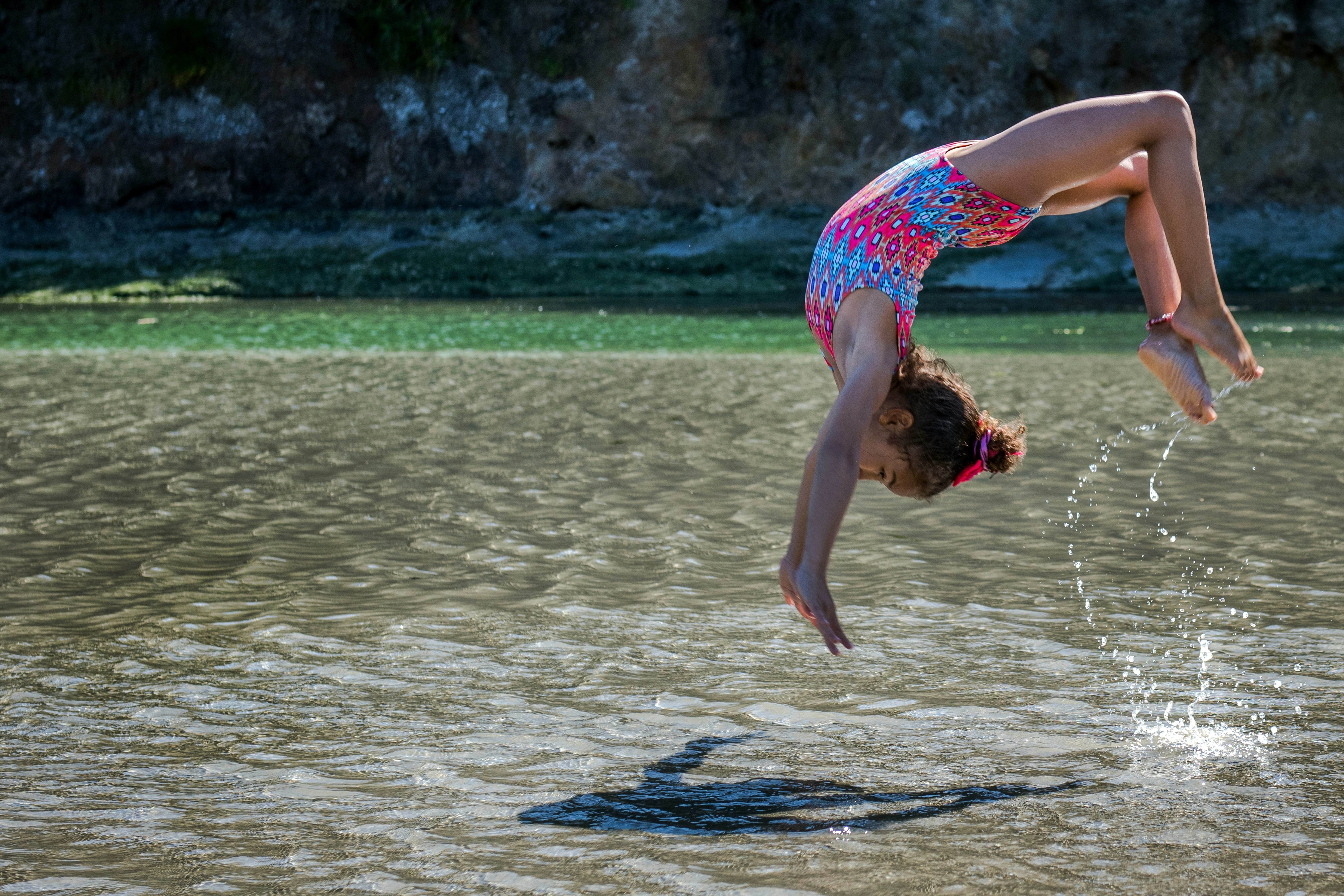 girl diving in body of water at daytime