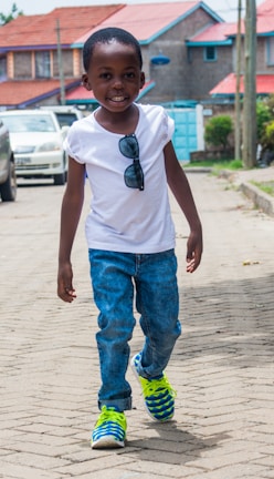 Smiling child crossing the street confidently with a parent holding their hand.