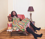 A colorful patterned dress styled with casual accessories on a rustic wooden chair.