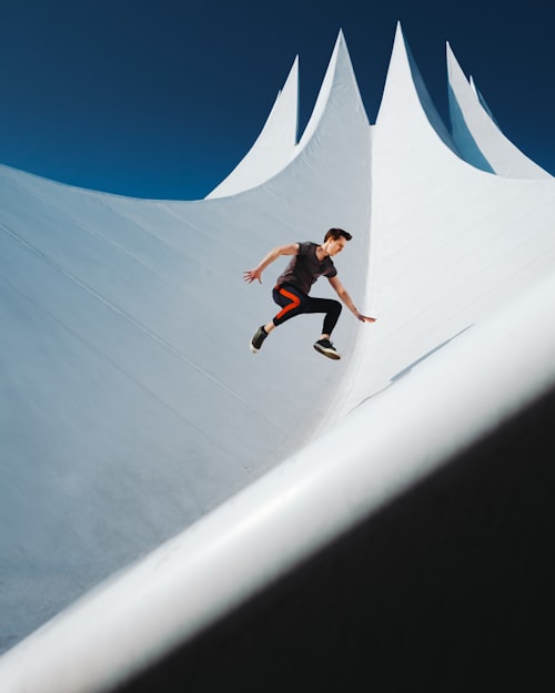 A man jumping in front of a white spiked structure under blue sky