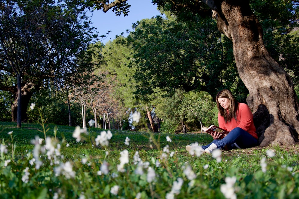 Mujer leyendo sentada al lado del árbol