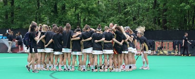 group of women doing group hug field hockey teams background