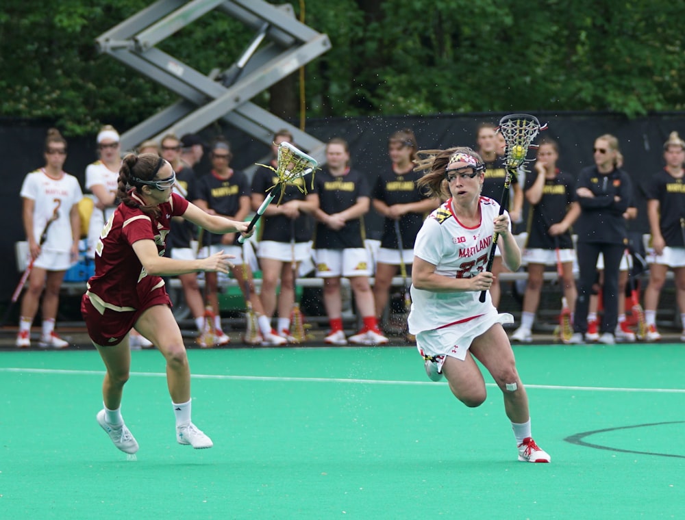 women playing lacrosse game during daytime