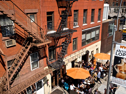 A bustling East Orange café patio filled with happy diners enjoying sunny afternoon meals.