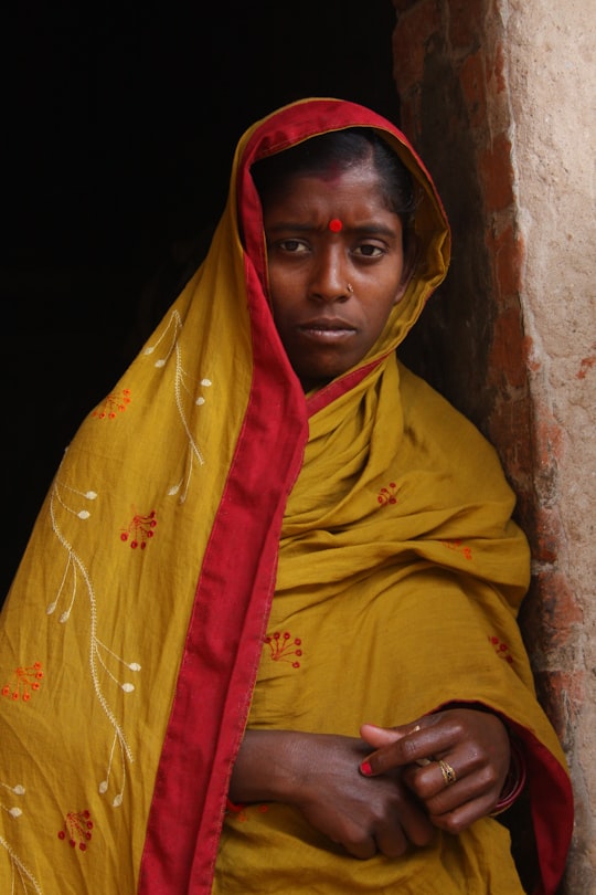 woman leaning on brown bricked wall in Odisha India