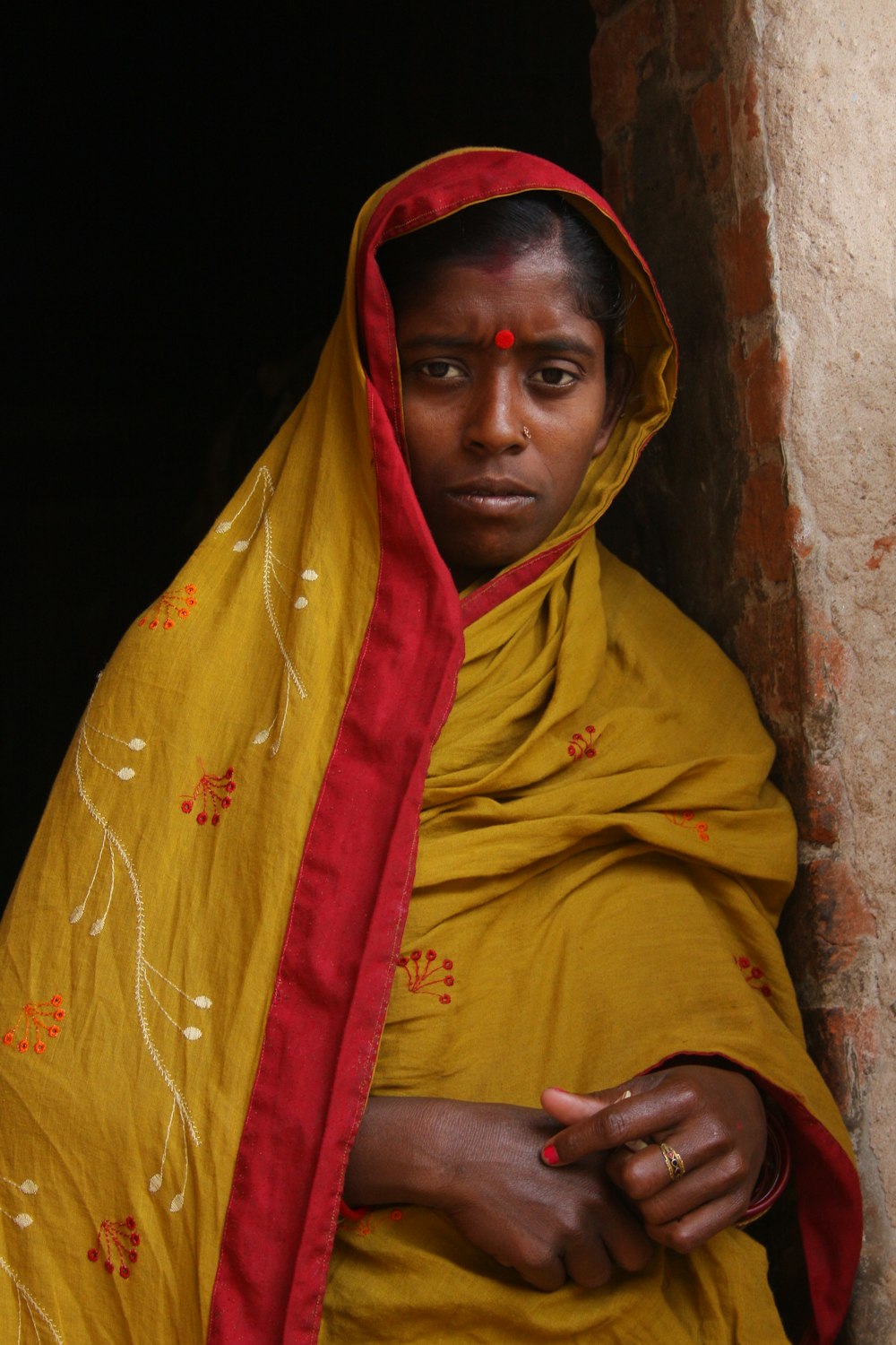 woman leaning on brown bricked wall