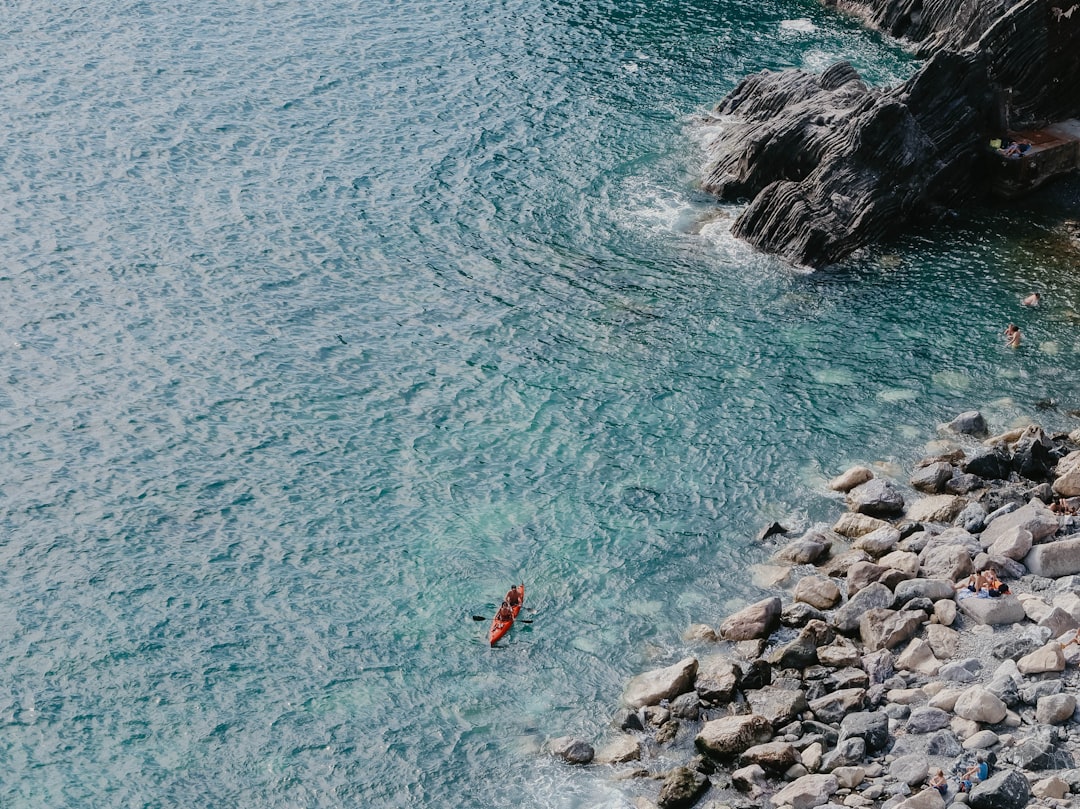 people paddling boat near boulders