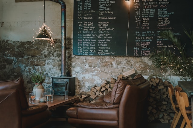 Cozy interior of The Smoke Craft with rustic wooden tables and a glowing smokehouse pit in the background.