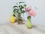 A minimalist wooden table set with a simple ceramic vase holding fresh greenery.
