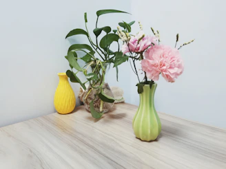 Minimalist floral centerpiece in a dark olive green vase on a cream linen tablecloth.