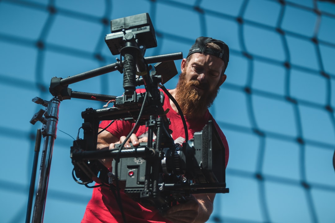 man using black professional camera, Jakob Owens, the buff nerd himself, makes the necessary adjustments to the Red camera to create the cleanest visuals possible.