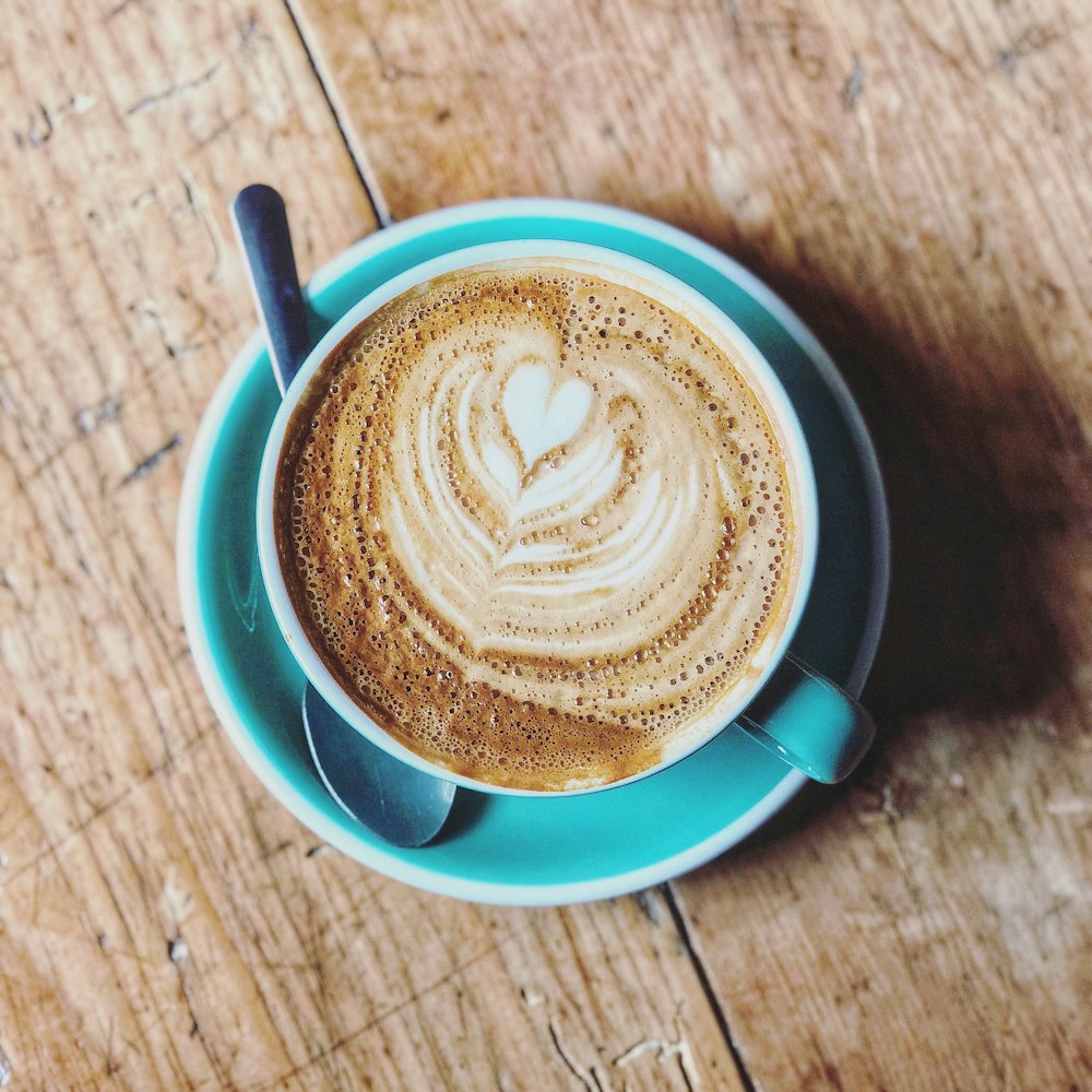 Taza de cerámica azul rellena de café con leche en platillo