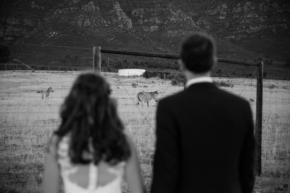 fotografia in scala di grigi dell'uomo e della donna davanti alla zebra