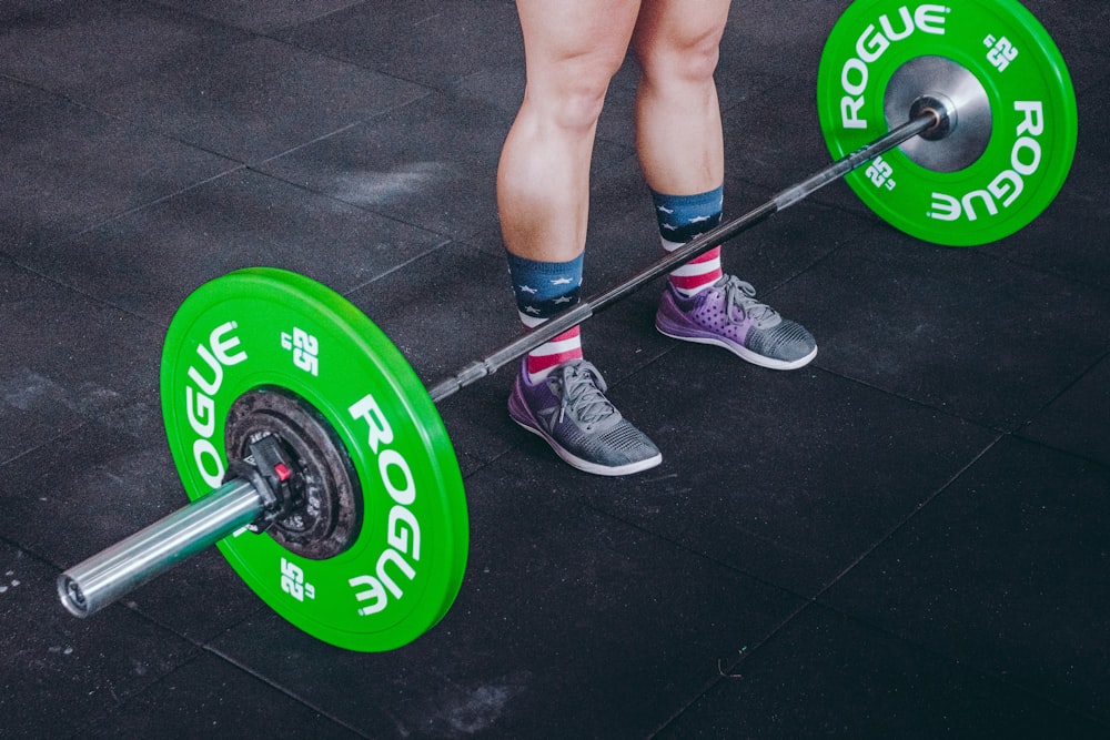 person standing in front of gray and green barbell