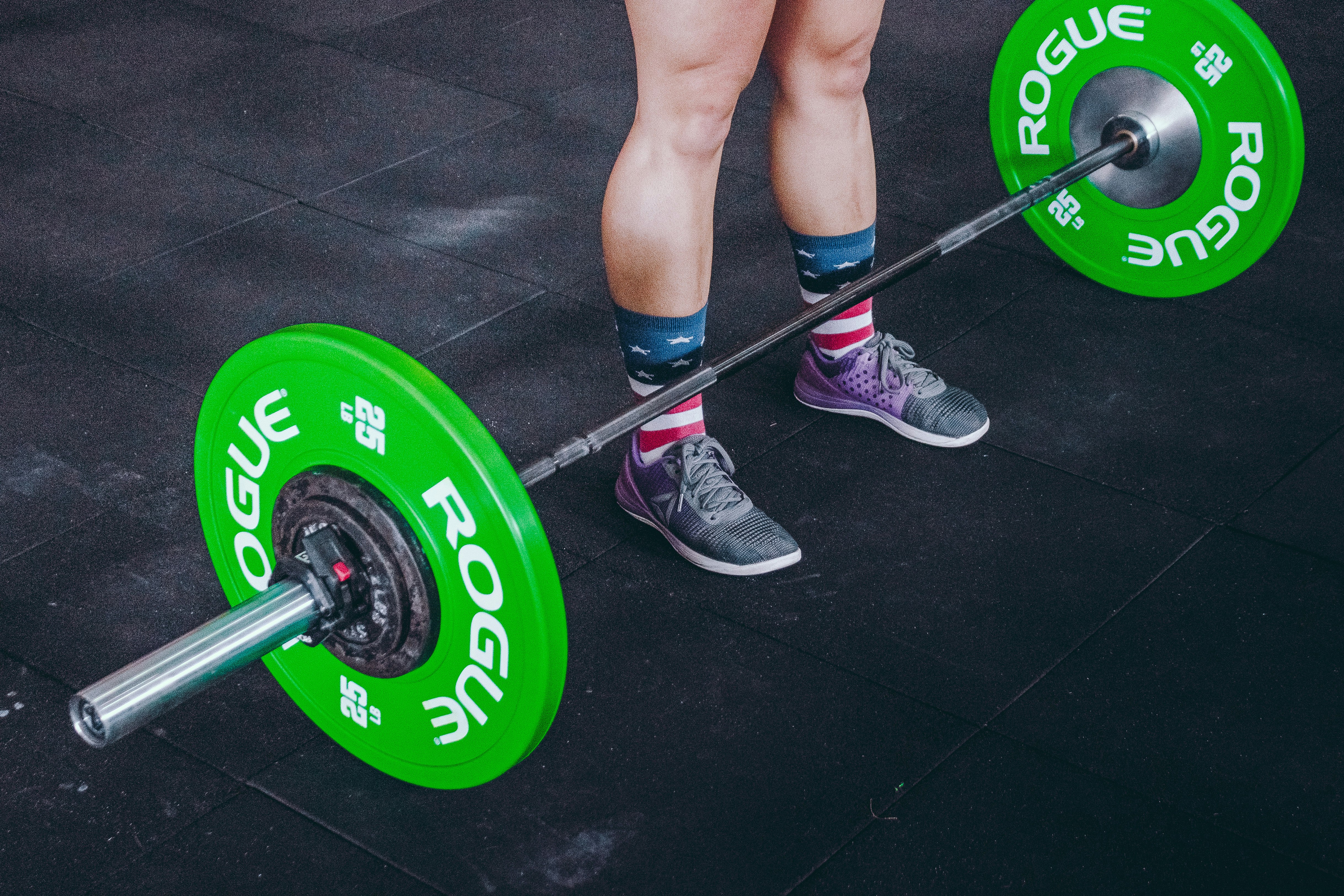 person standing in front of gray and green barbell