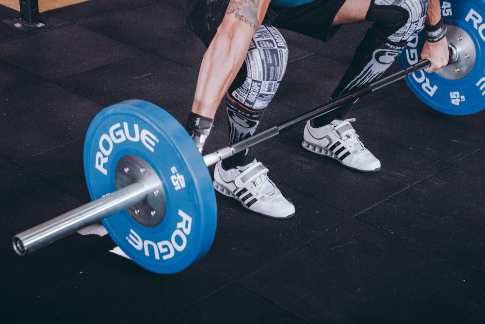 person weight holding blue and gray Rogue barbell