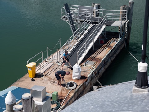 Workers conducting maintenance on a weathered concrete dock.