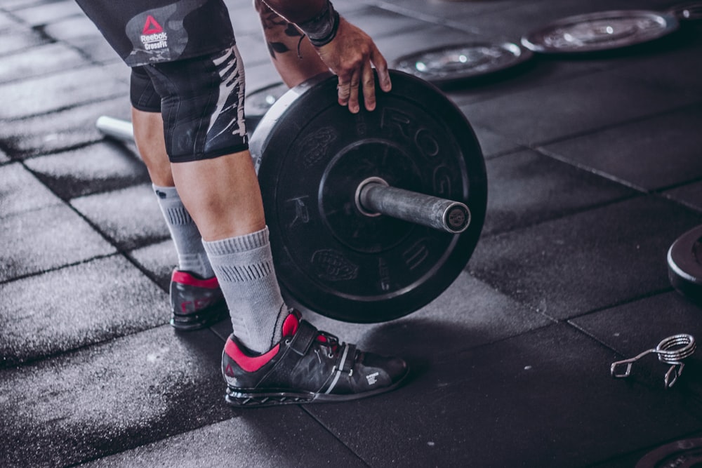 person holding black barbell plate