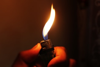 A glowing MK lighter flame illuminating a cozy evening setting outdoors.