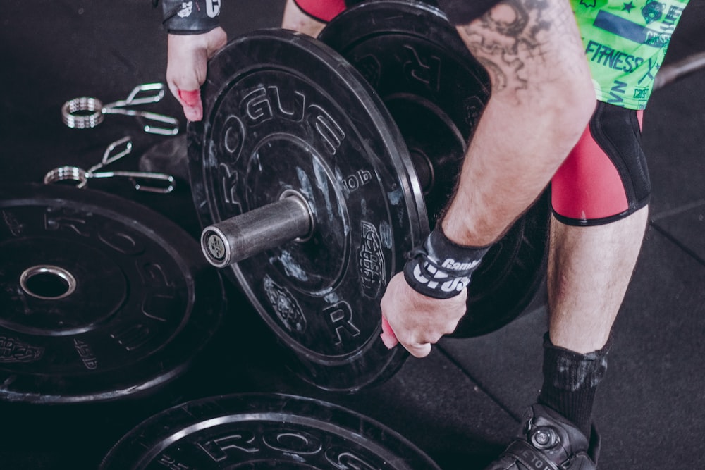 man holding black Rogue weight plate