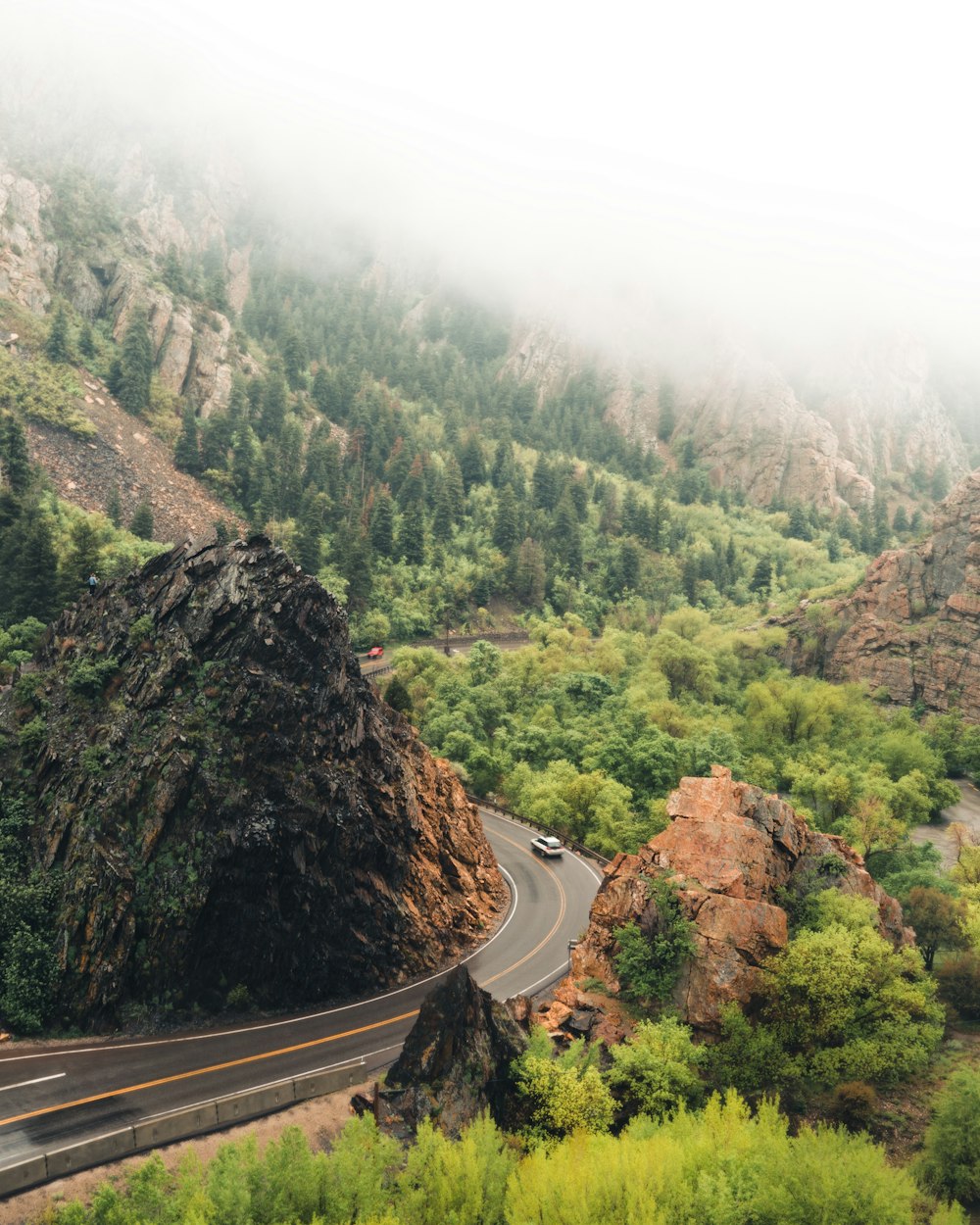 gray vehicle on road surrounded by mountain and tree at daytime