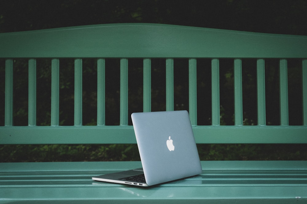 allumé MacBook Pro sur le banc en bois blanc