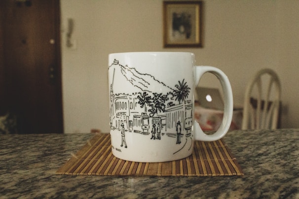 A trendy portable coffee mug with a dripdrop lk logo on a city background.
