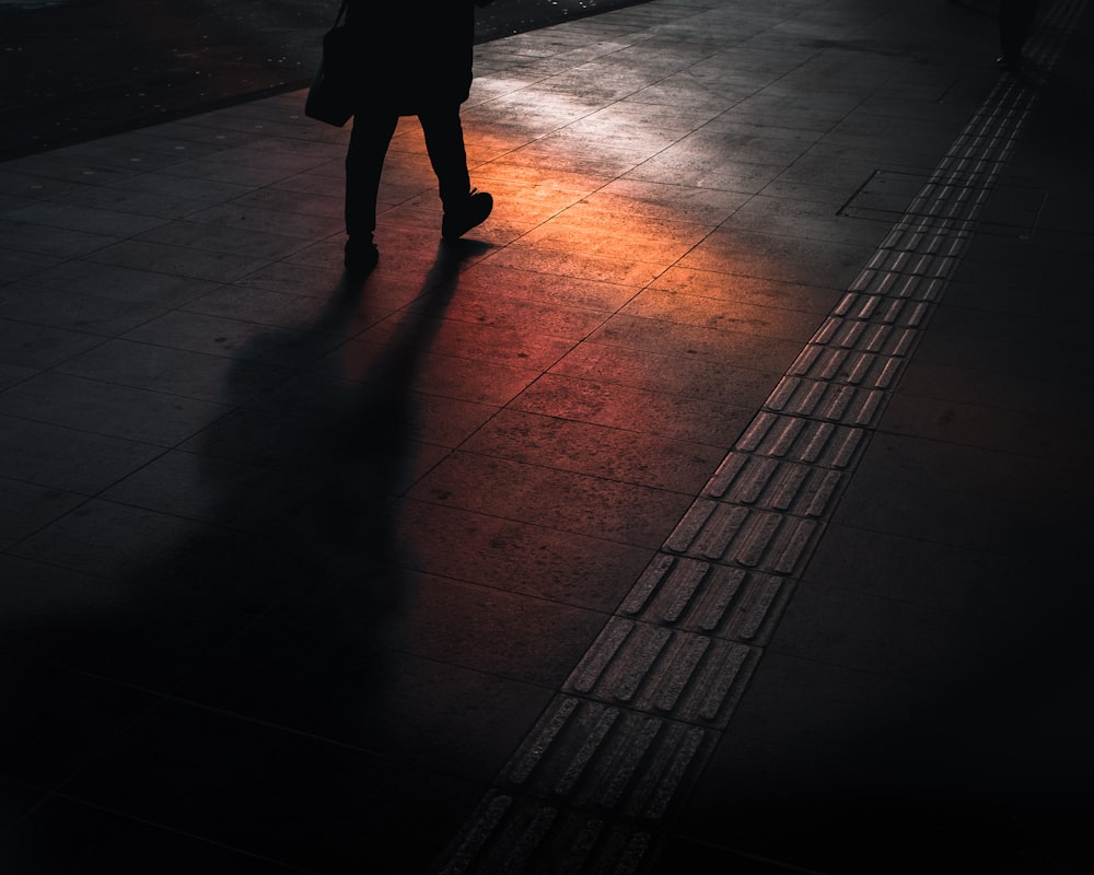 silhouette of person walking on gray floor tile