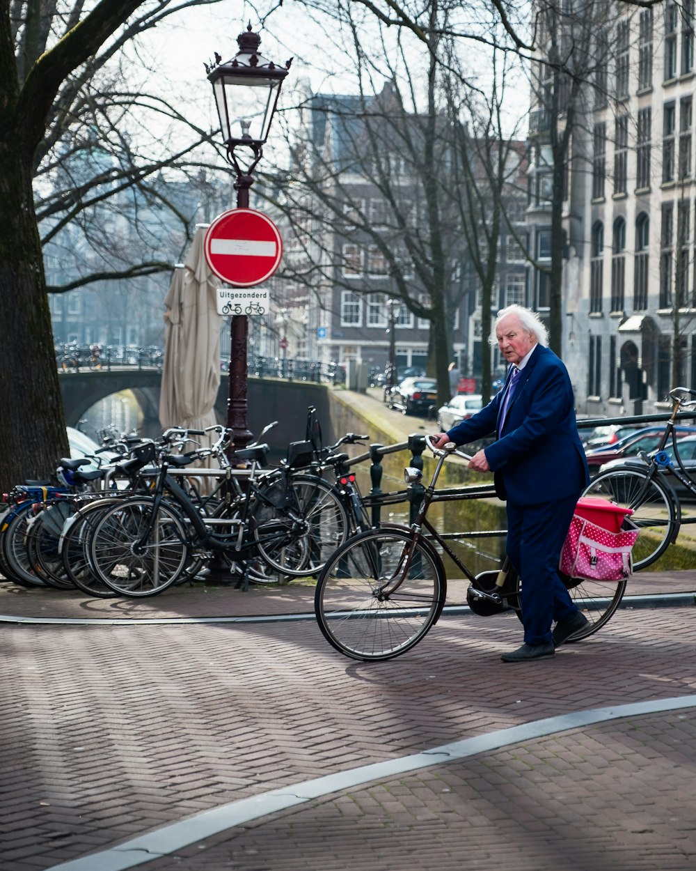 man wearing black notched lapel suit jacket holding bike