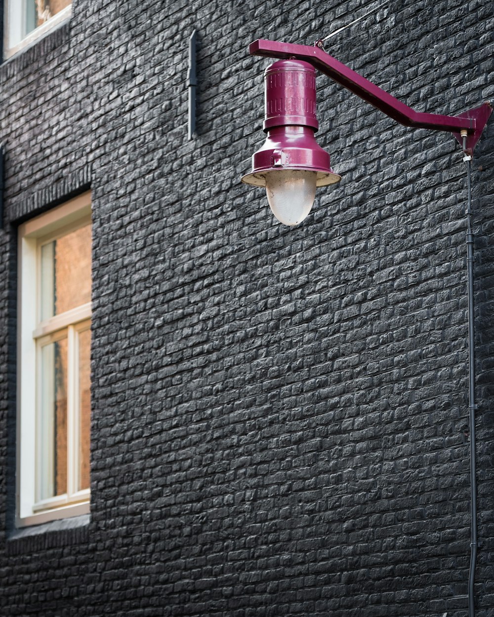 purple street lamp on black wall bricks
