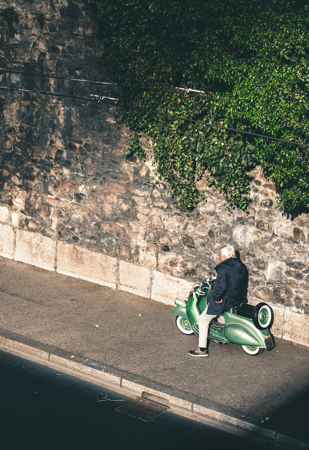 man riding a green motor scooter