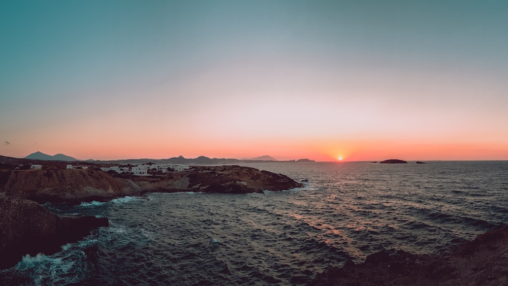 brown rock formation near sea at sunset