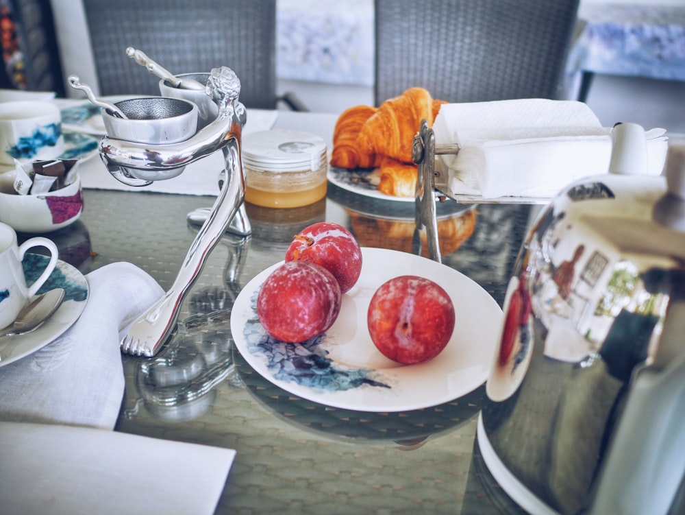 three red apple fruits on white ceramic plate