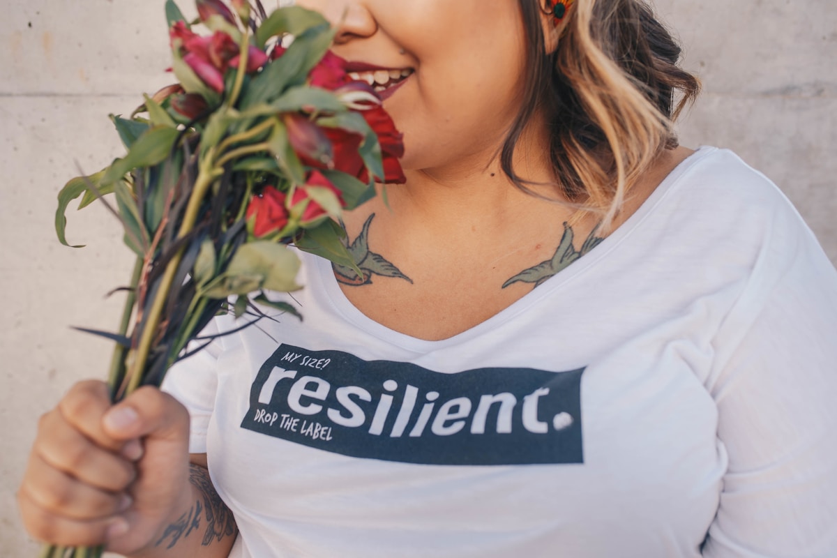 Strong, resilient woman smiles holding a bunch of flowers.