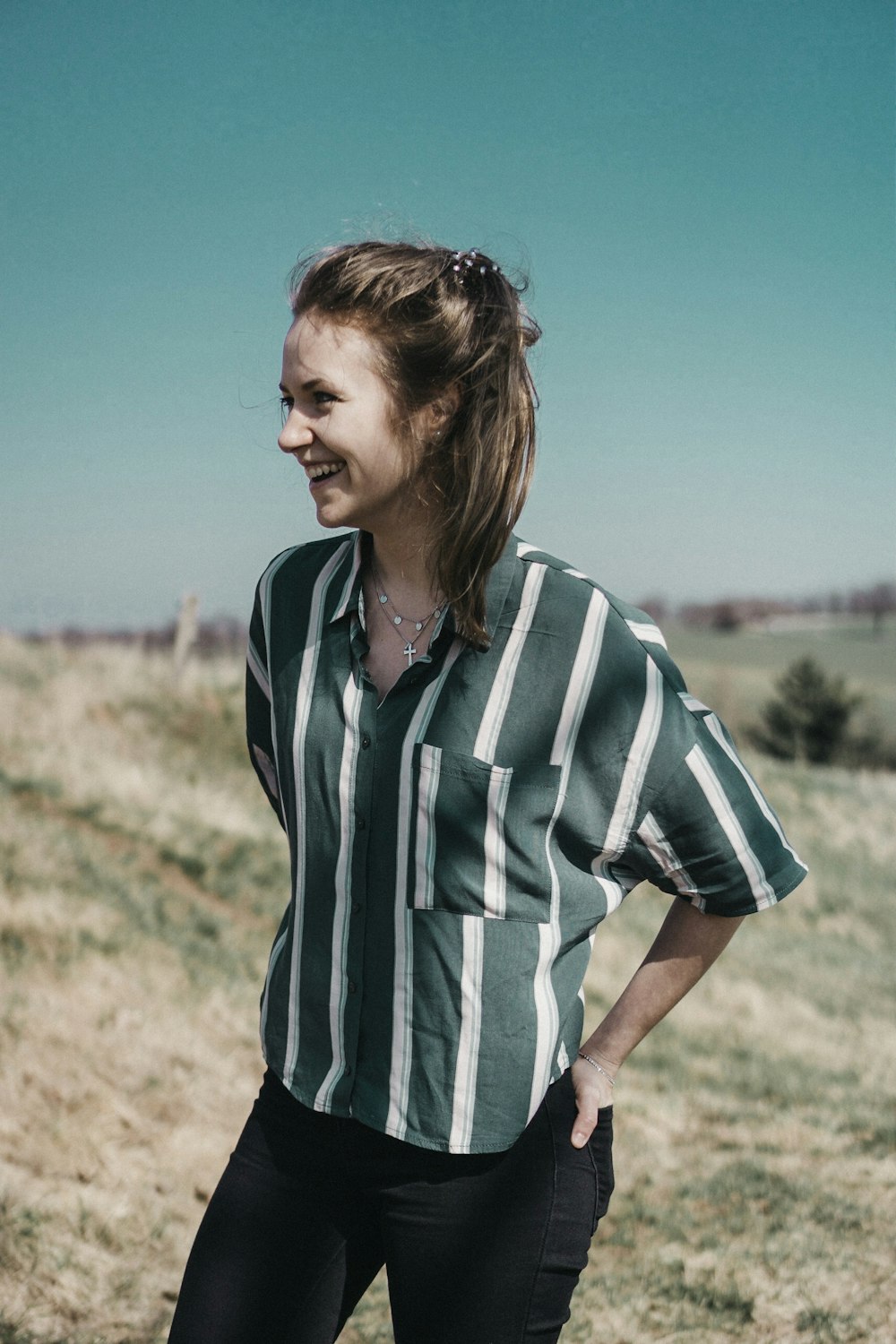 woman standing on green grass while hands in black pocket