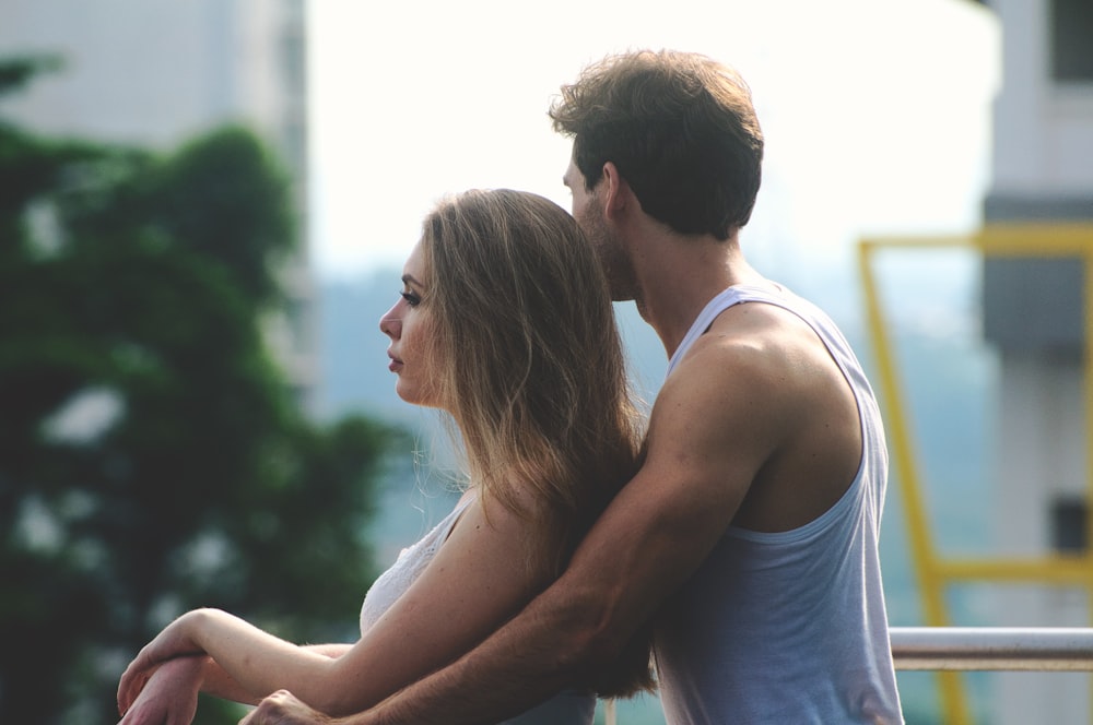 man hogging woman leaning on rail